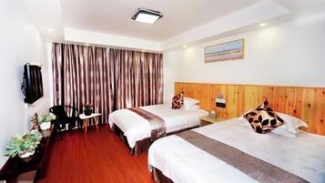 Habitación de hotel con dos camas, cabecero de madera, televisor de pantalla plana montado en la pared, una mesita y una silla.