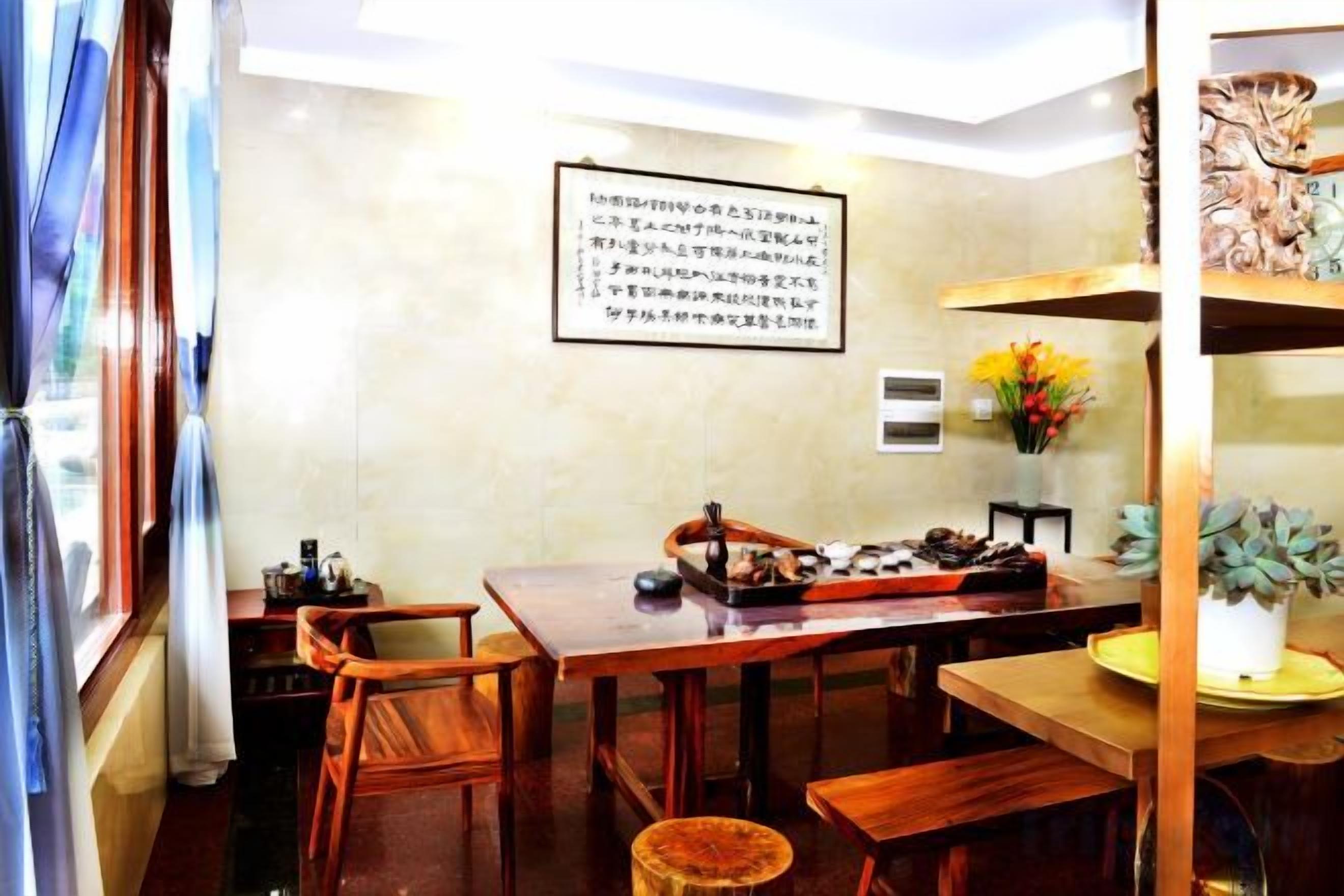 A dining area with a wooden table and chairs, a vase with flowers, and a wall-mounted sign.
