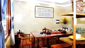 A dining area with a wooden table and chairs, a vase with flowers, and a wall-mounted sign.