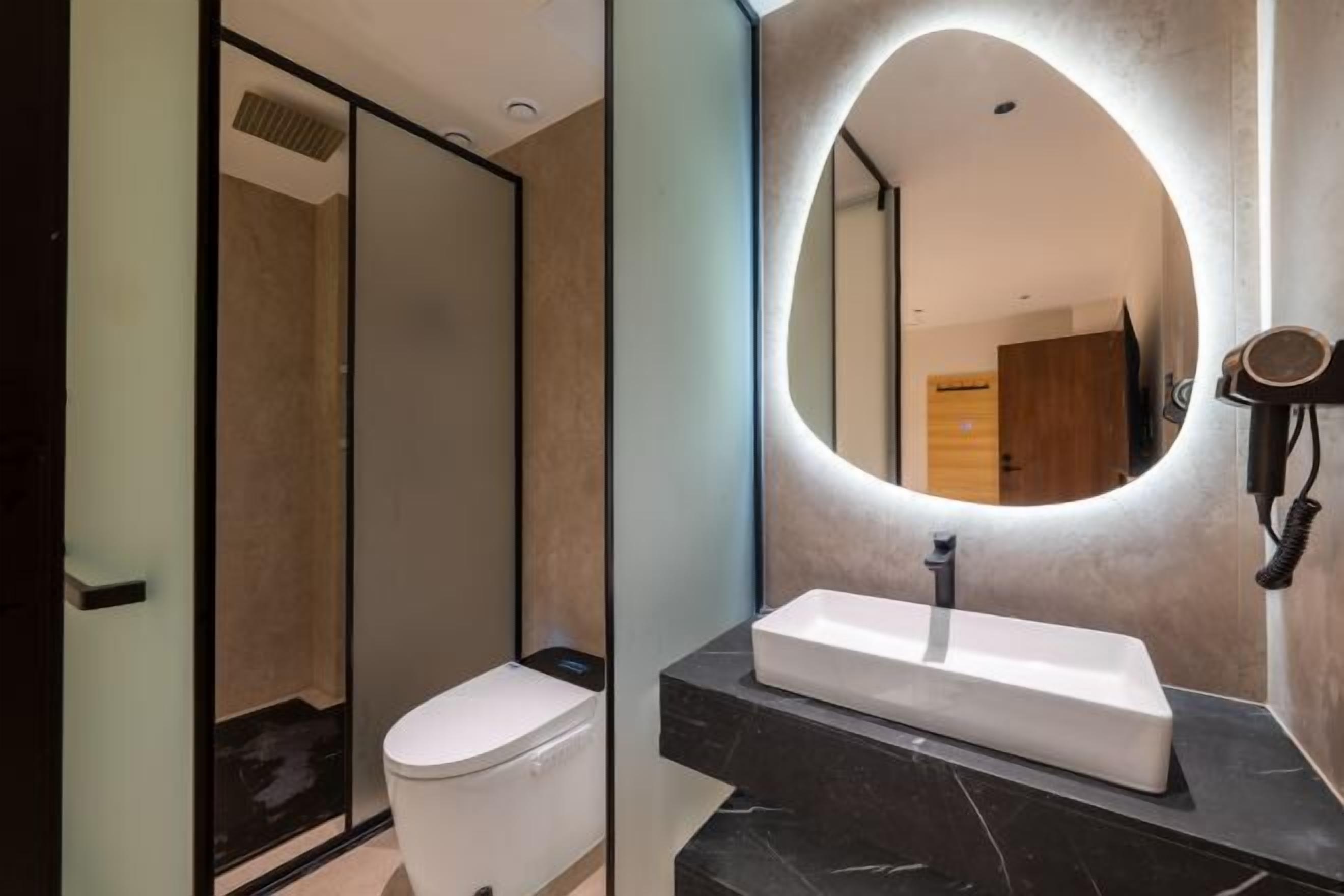 Une salle de bain moderne avec des toilettes, un lavabo rectangulaire et un grand miroir.