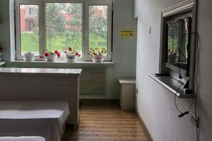A hotel room with a bed, a window with potted plants, a radiator, and a sign on the wall. - Yichun Wengxinyuan Family Guesthouse (Tangwang County)