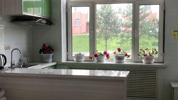 A kitchen with a window, white cabinets, and a sink. - Yichun Wengxinyuan Family Guesthouse (Tangwang County)