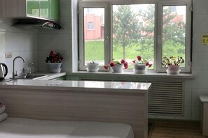 A kitchen with a window, white cabinets, and a sink. - Yichun Wengxinyuan Family Guesthouse (Tangwang County)