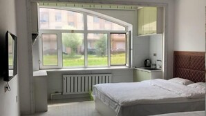 A bedroom with a large window, a bed, a radiator, and a TV mounted on the wall. - Yichun Wengxinyuan Family Guesthouse (Tangwang County)