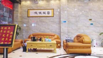 A hotel lobby with a marble wall, two leather sofas, a coffee table, and a sign with Chinese characters.