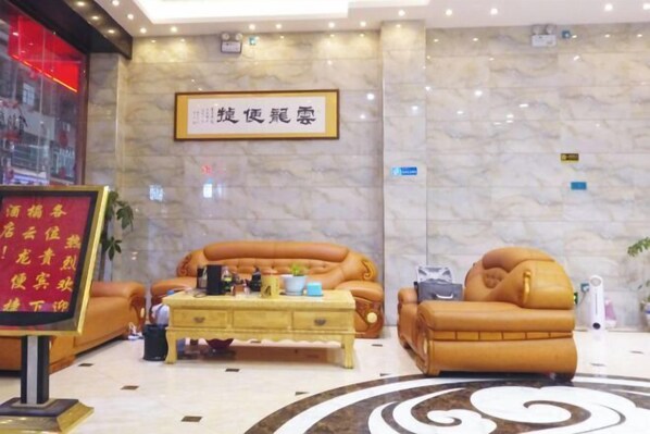 A lobby with a marble wall, two leather sofas, a wooden coffee table, and a framed sign. - Jianghua Yunlong Convenient Hotel (Jianghua)