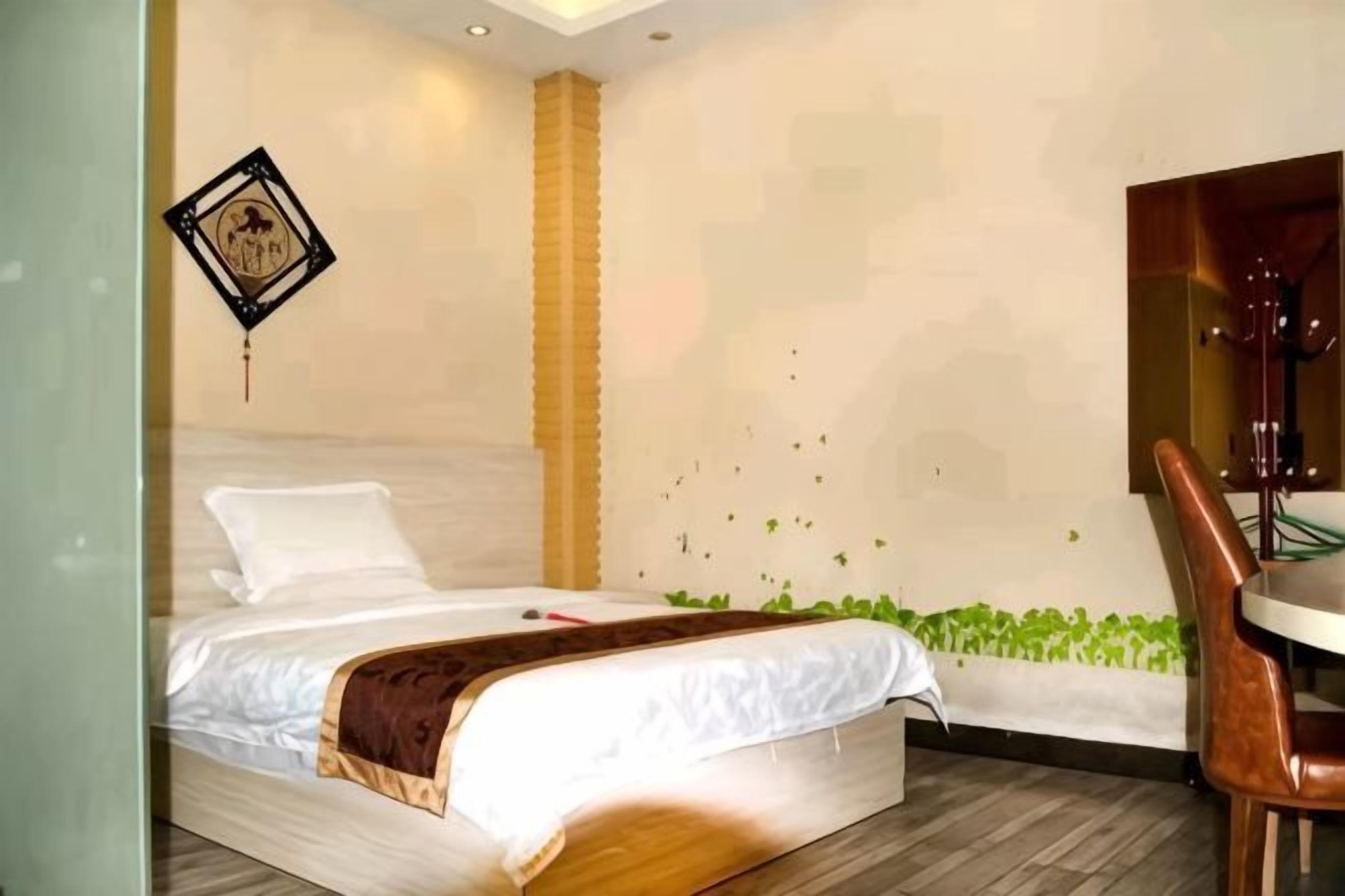 A bedroom with a bed, a chair, a wall-mounted TV, and a decorative wall piece.