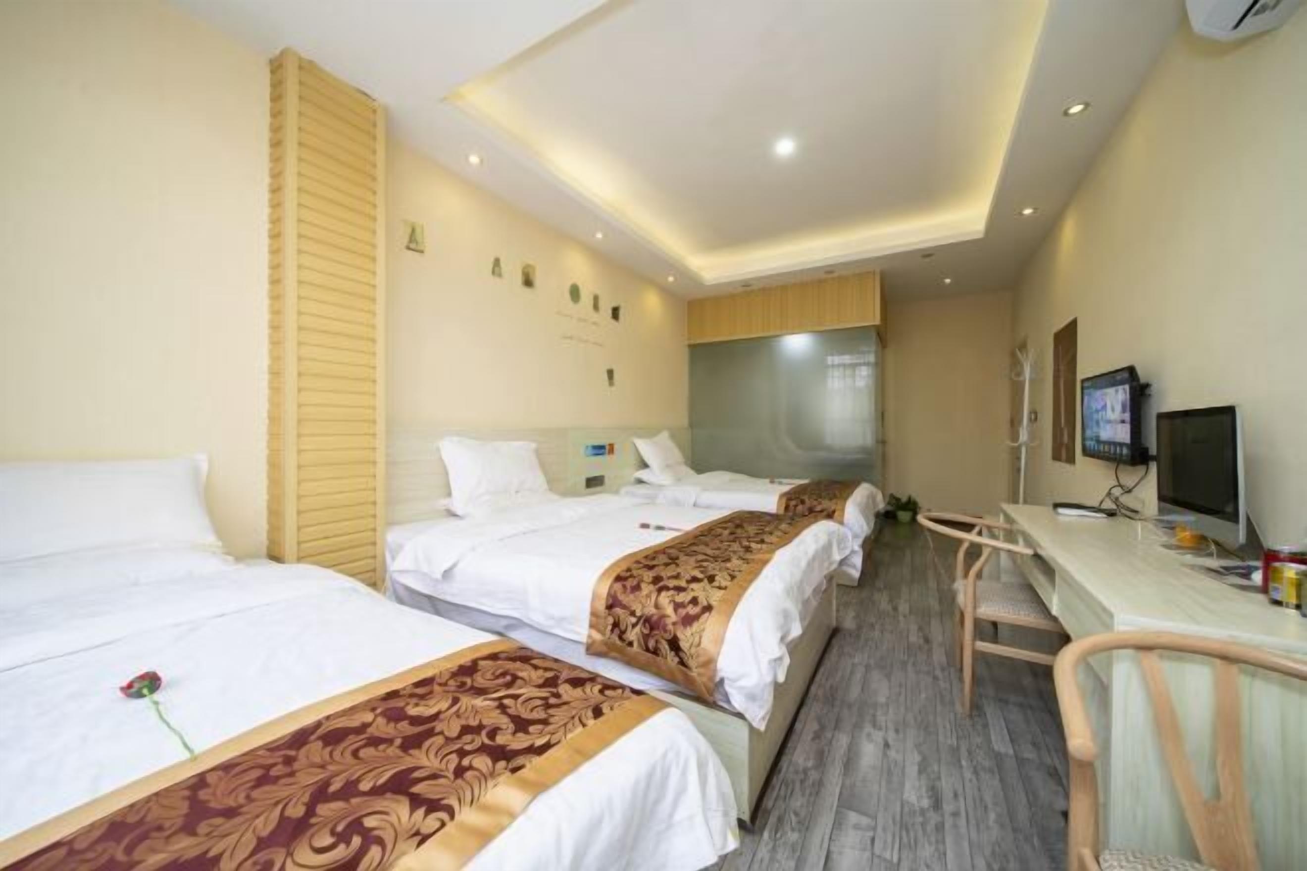 A hotel room with two beds, a desk, and a television.