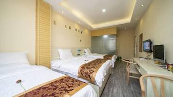 A hotel room with two beds, a desk, and a television.