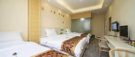 A hotel room with two beds, a desk, and a television.