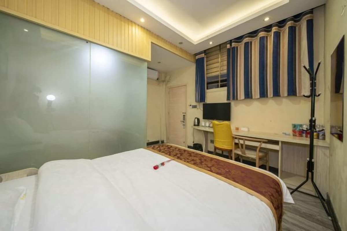 A hotel room with a bed, a desk, a chair, and a television.