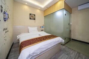 Habitación de hotel con cama, armario, una pared decorada y una pequeña mesa.