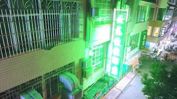 A multi-story building with barred windows and a green-lit entrance.