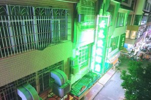 A multi-story building with barred windows and a green-lit entrance. - Jianghua Yunlong Convenient Hotel (Jianghua)
