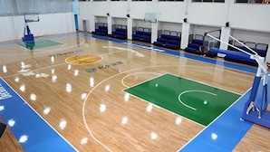 A basketball court with blue and green markings, a basketball hoop, and blue seating areas. - Beitou Resort Metro Inn (Taipei)