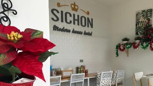 Ett hotellrum med en matplats som har vita stolar, ett bord och en väggskylt med texten ”SICHON Modern home hotel”.