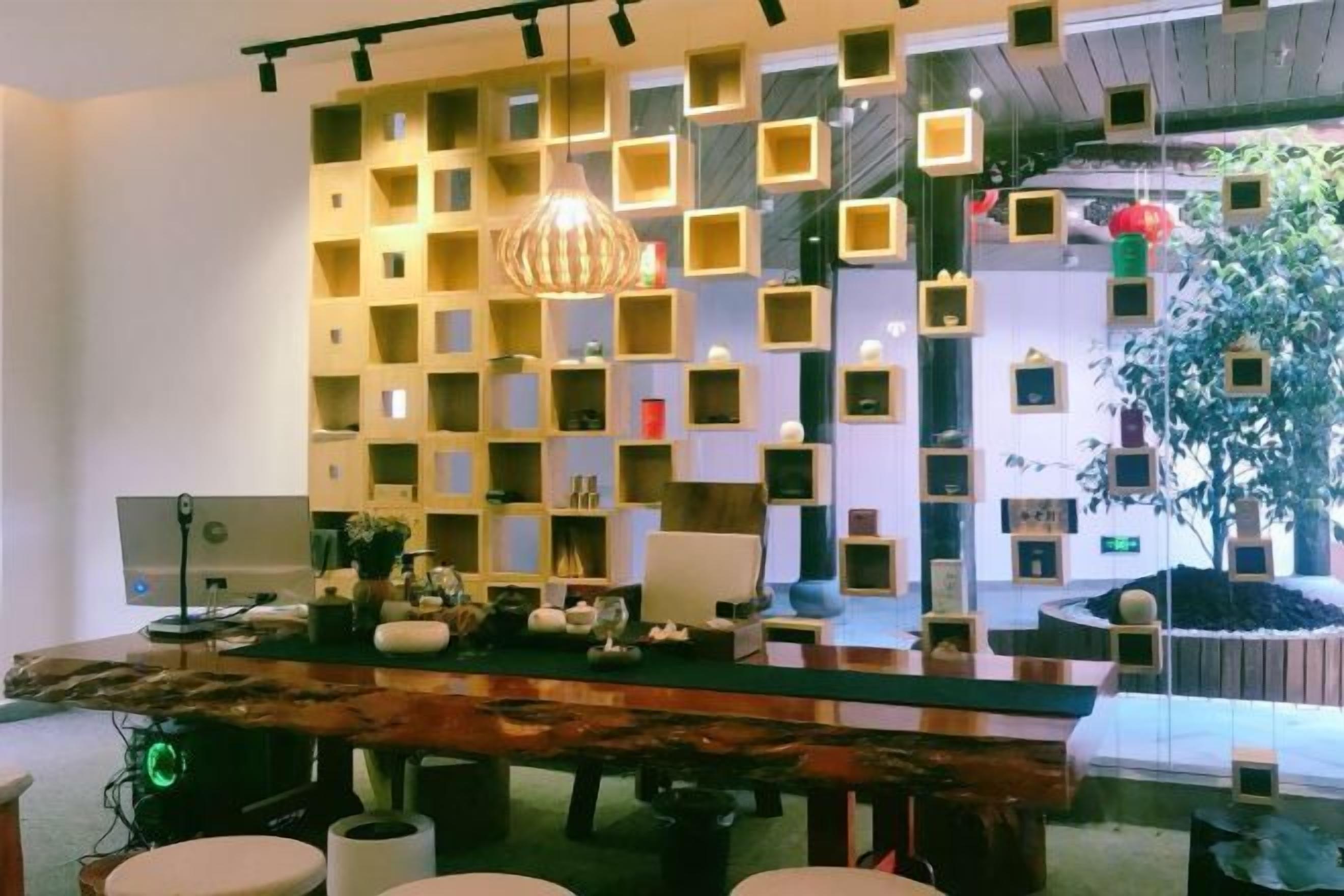 A modern interior with a wooden table, multiple chairs, a wall-mounted shelf unit, and a hanging light fixture.