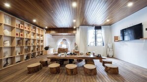A wooden interior with a central table, stools, and shelves with various items. - Yunyi Hot Spring Zangpin Inn (Tengchong)