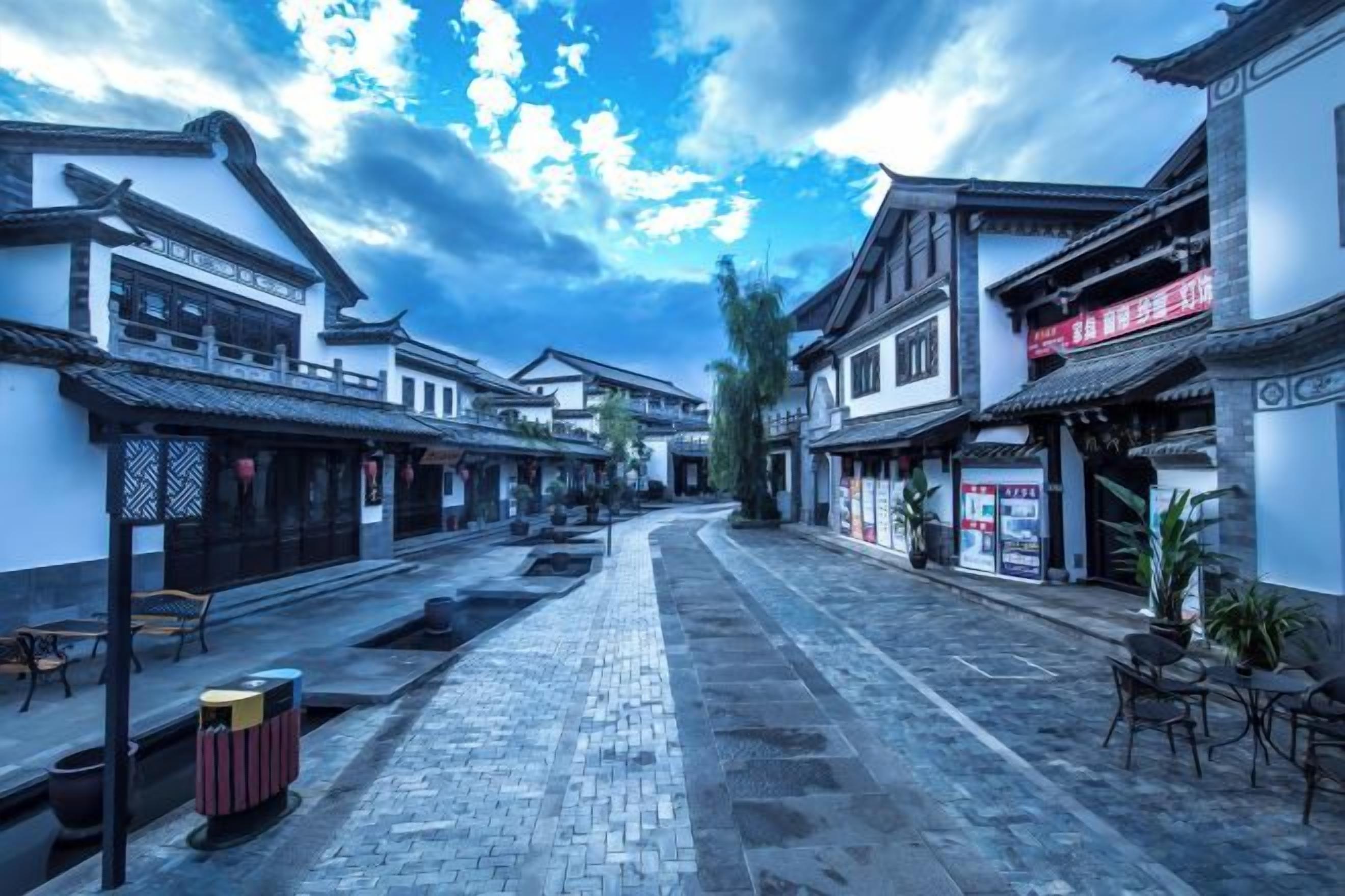 A traditional street with buildings, a paved walkway, and outdoor seating.