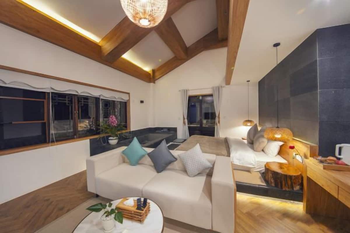 A modern living room with a sofa, a coffee table, and a dining area with a wooden table and chairs.