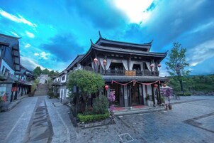 A traditional building with a tiled roof, a central entrance, and a staircase leading to the upper level.