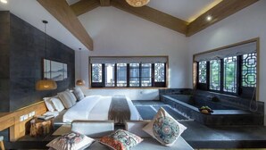 A modern bedroom with a large bed, a sitting area, a bathtub, and a view of the outdoors through large windows. - Yunyi Hot Spring Zangpin Inn (Tengchong)