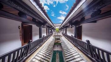 A corridor with a central walkway flanked by walls, leading to a door at the end.