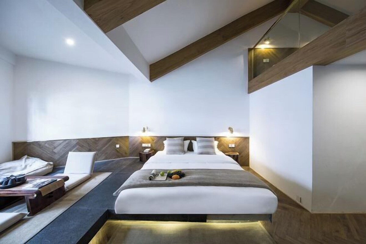A modern hotel room with a bed, bedside tables, and a built-in bench.