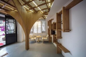 A modern interior with wooden beams, a curved doorway, a seating area with two chairs and a small table, and built-in wooden shelves.