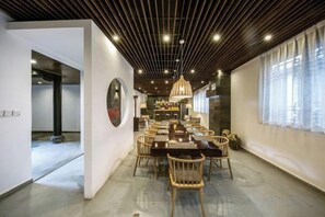 A dining area with a long table, chairs, and a hanging light fixture.
