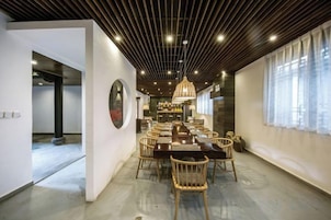 Un comedor con una mesa larga, sillas y una lámpara colgante.