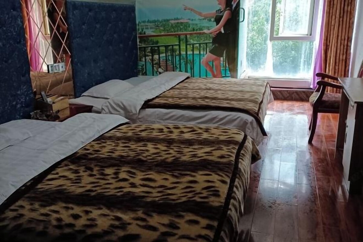 Hotellihuone, jossa on kaksi sänkyä, parveke, jolta on näkymä, ja puulattia.