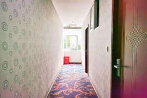 A hallway with patterned walls and a carpeted floor leading to a door with a decorative design. - Bazhong city home business hotel (Bazhong)