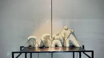 Una mesa con tres esculturas blancas frente a una pared lisa.