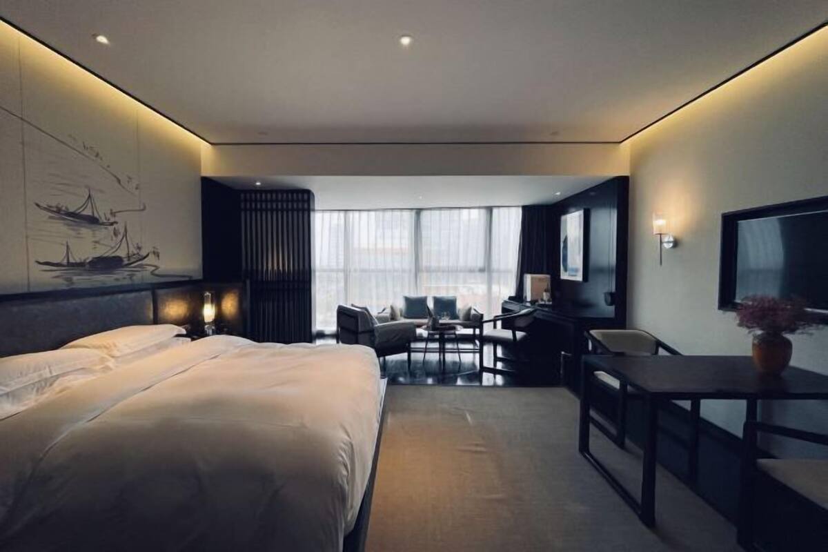 Une chambre d’hôtel moderne équipée d’un grand lit, d’un bureau, d’une chaise et d’un téléviseur.