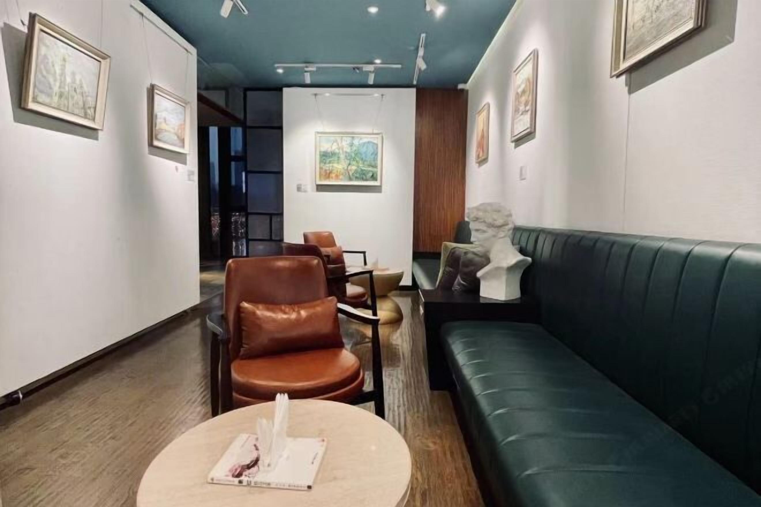 A modern interior with a green sofa, leather chairs, and artwork on the walls.