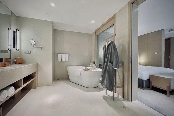 A modern bathroom with a bathtub, a vanity with a mirror, and a shower area.