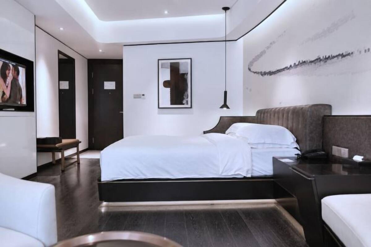 Une chambre à coucher moderne, comprenant un lit, des tables de chevet, un bureau, une chaise et un téléviseur.