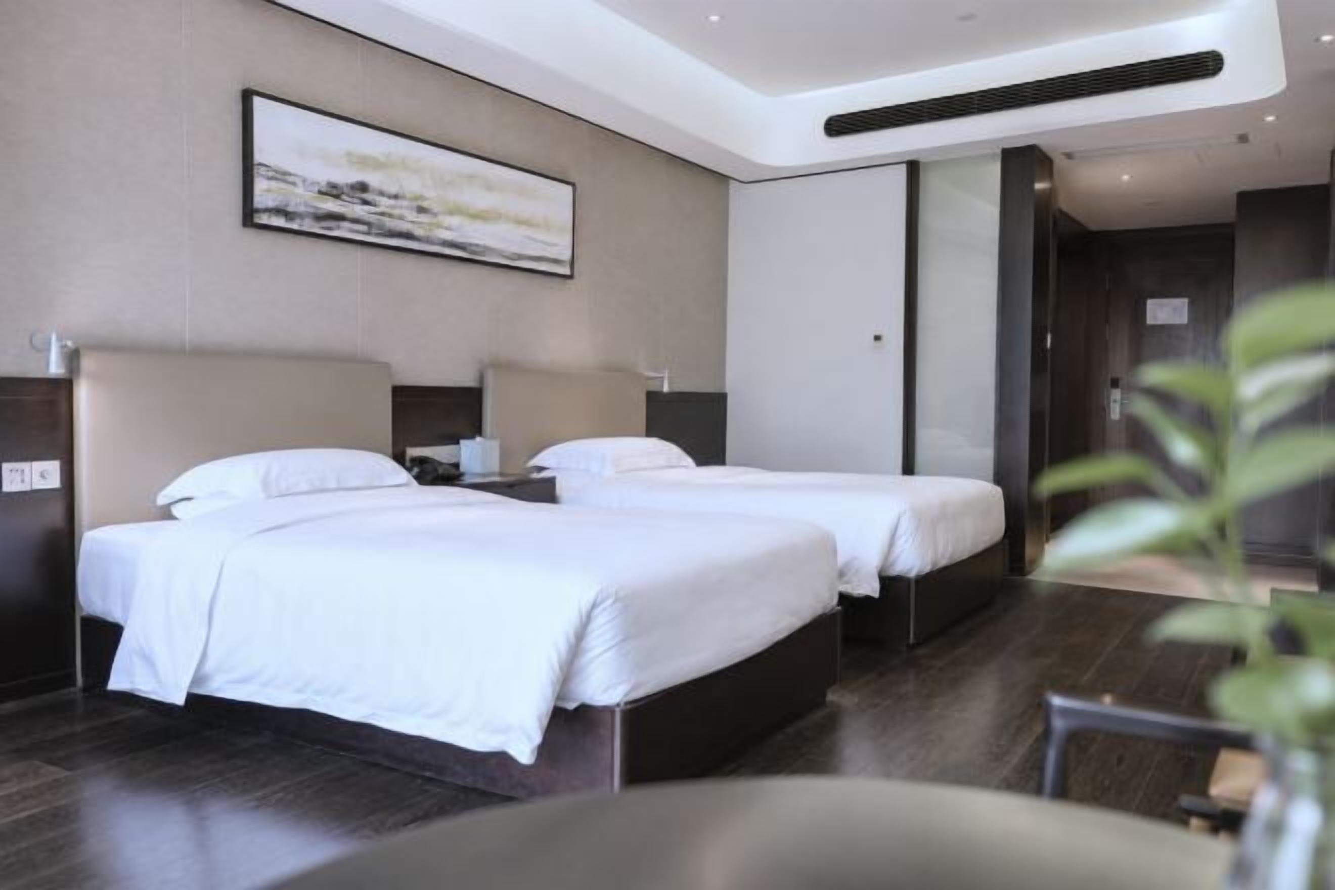 A hotel room with two beds, a large window, and a modern design.