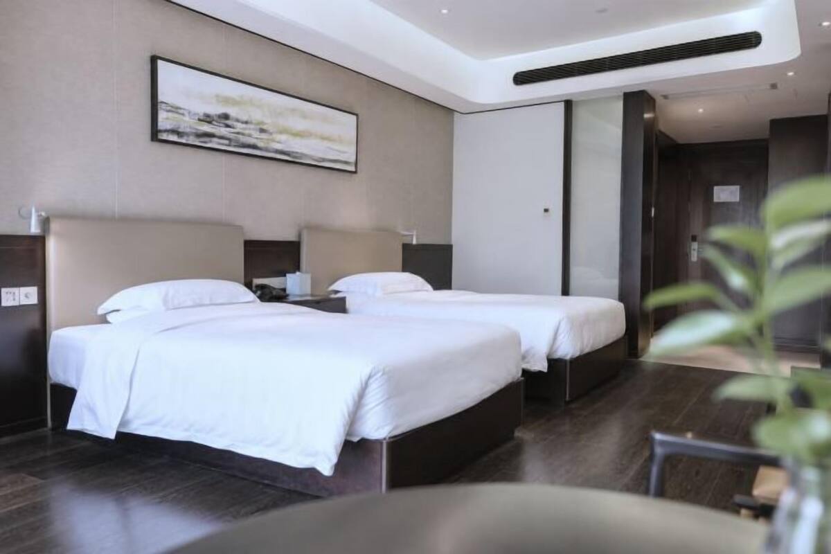 Une chambre d’hôtel avec deux lits, une grande fenêtre et un design moderne.