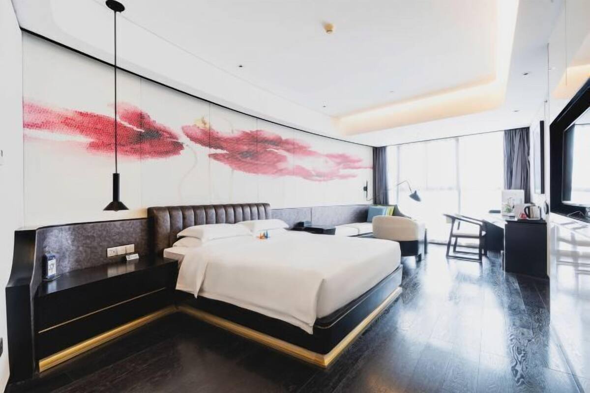Une chambre d’hôtel moderne, dotée d’un grand lit, d’un bureau et offrant une vue sur la ville.