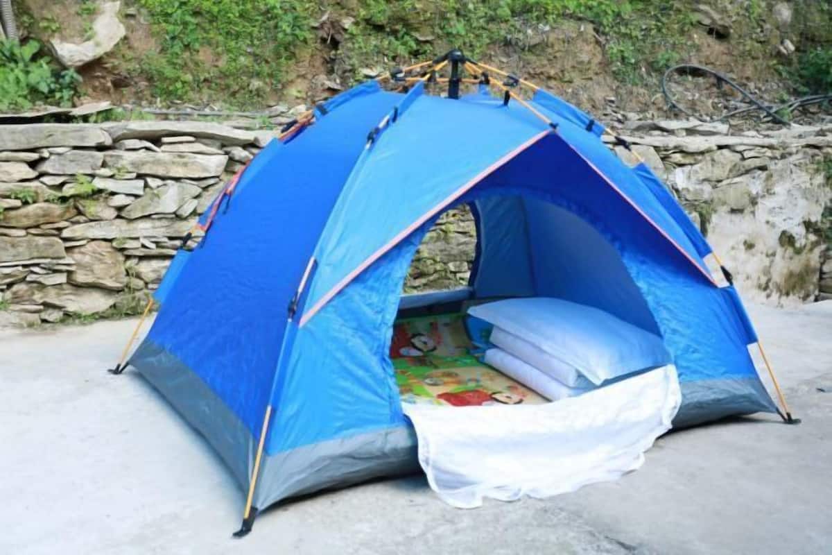 Una carpa azul con interior blanco, ubicada frente a una pared de piedra.