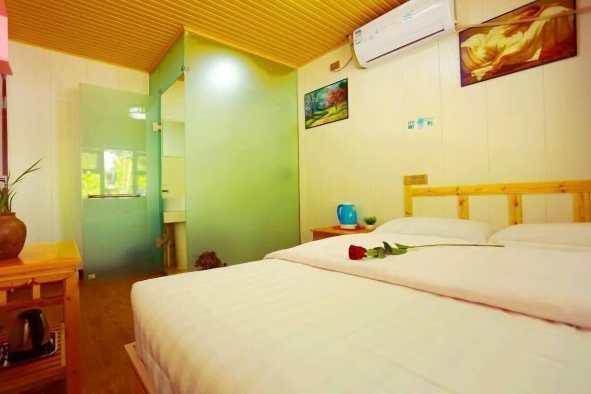 Habitación de hotel con cama, mesita de noche, aire acondicionado de pared y un cuadro.