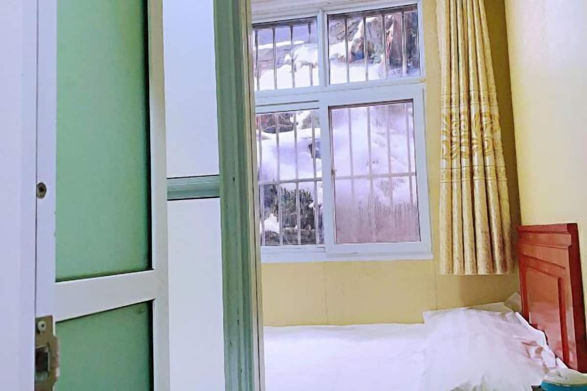 Una habitación con una cama, un ventanal con vista a un paisaje nevado y una puerta.