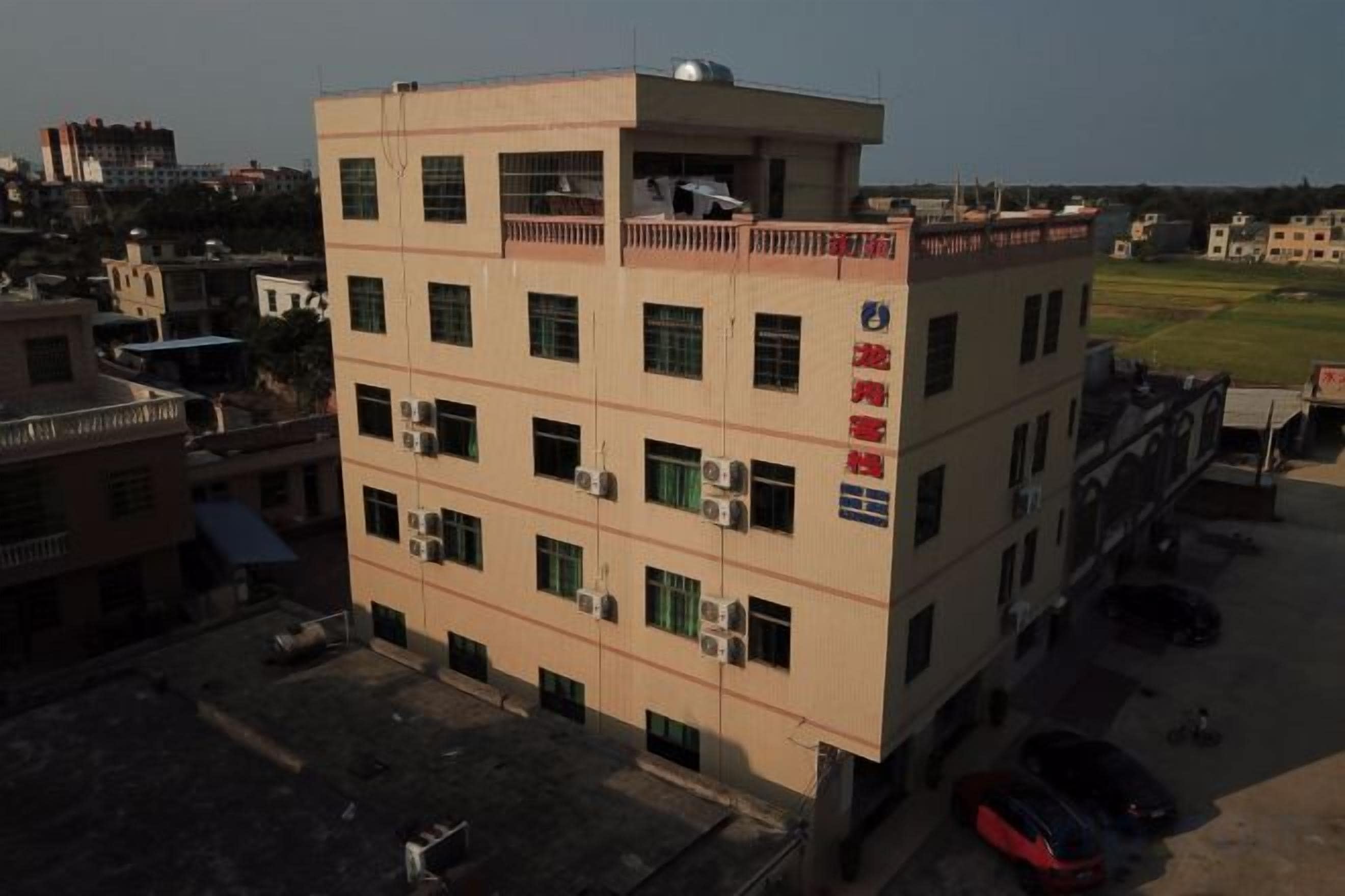 A multi-story building with a flat roof, several windows, and a sign with red text.