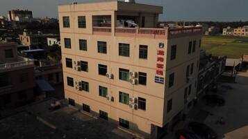 A multi-story building with a flat roof, several windows, and a sign with red text.