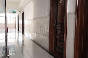 A corridor with a polished floor, wooden doors, and a staircase. - longzhou hostel (Wanning)