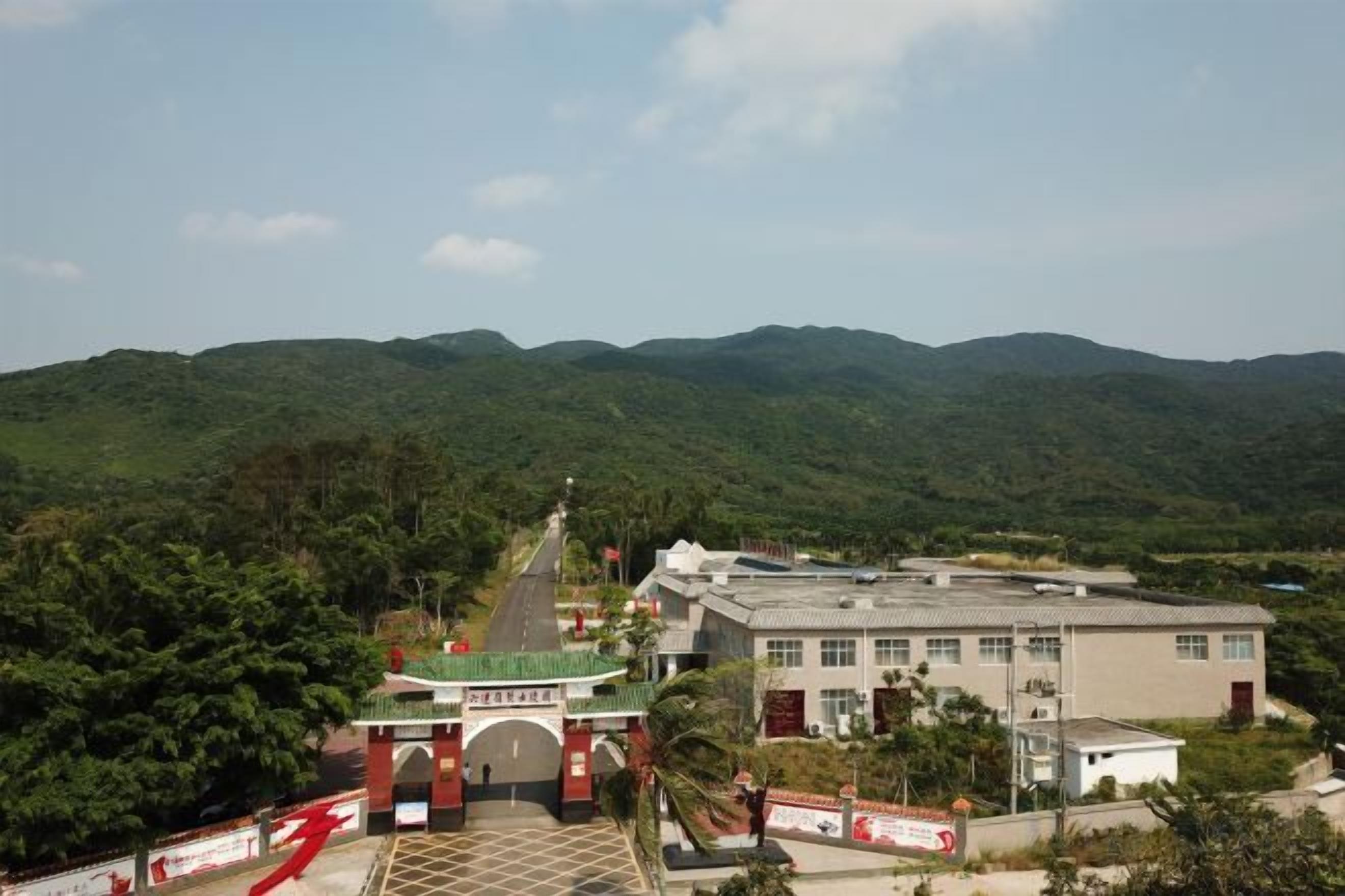 A building with a traditional entrance gate, surrounded by lush green hills.