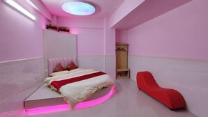 A modern bedroom with a bed, a red chair, and a vanity with a mirror. - longzhou hostel (Wanning)
