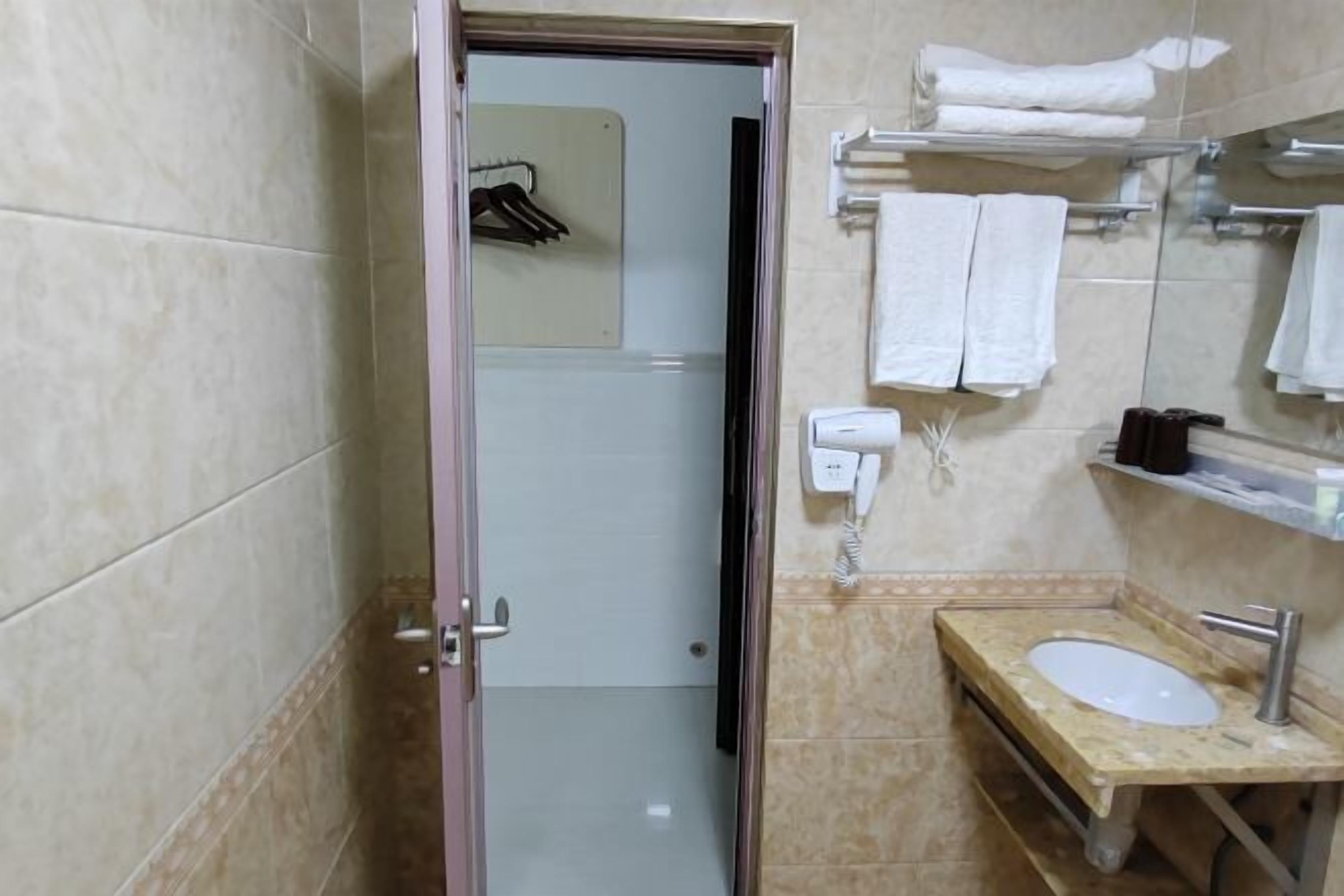 Ein Badezimmer mit Waschbecken, Spiegel, Handtuchhalter und Duschbereich.